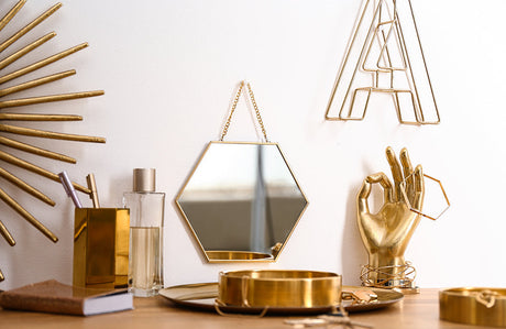 Komposition mit goldenen Accessoires auf einem Schminktisch.