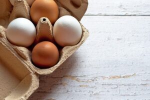 In einer Eierpappe stecken zwei weiße und zwei braune Eier