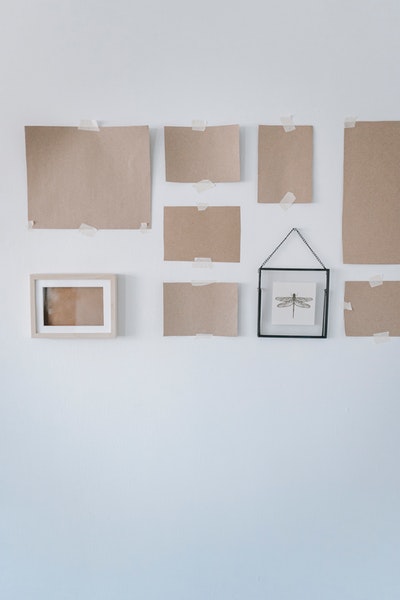Um eine Bilderwand zu gestalten, hängen Papier-Dummys an einer Wand