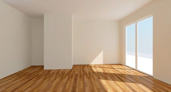 Ein leeres Zimmer mit weißen Wänden und Holzfußboden ist zu sehen