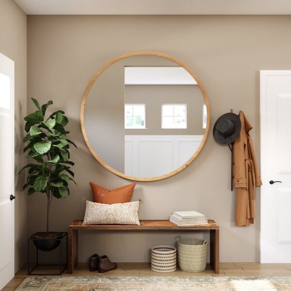 Ein runder Spiegel hängt an eine Wand, die mit Möbeln und Gegenständen in Erdtönen dekoriert ist. 