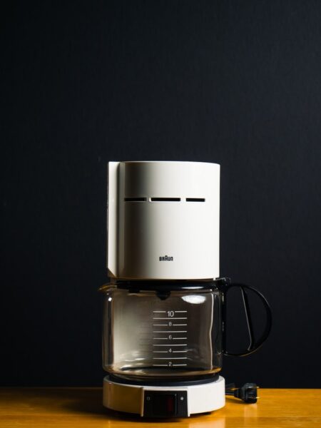 Eine Filterkaffeemaschine, in der sich ein bisschen Kaffee befindet, steht auf einem Holztisch