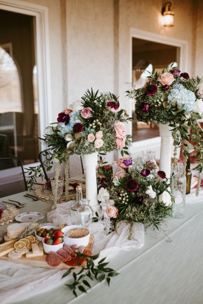 Eine Vielzahl an Blumen in Vasen und Gestecken schmücken einen gedeckten Tisch. 
