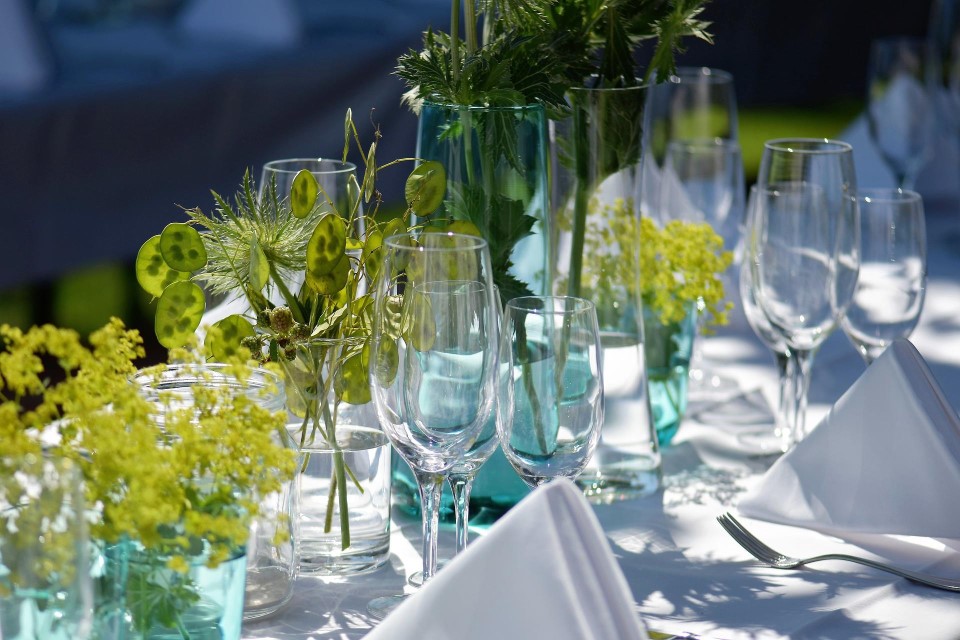 Ein weiß gedeckter Tisch, dekoriert mit Pflanzen.