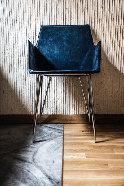 Ein Stuhl mit Beinen aus Metall, samtigem blauen Polster sowie Rücken- und Armlehnen