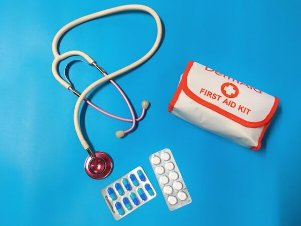Stethoskop, First-Aid-Kit und Pillen auf blauem Hintergrund liegend. 