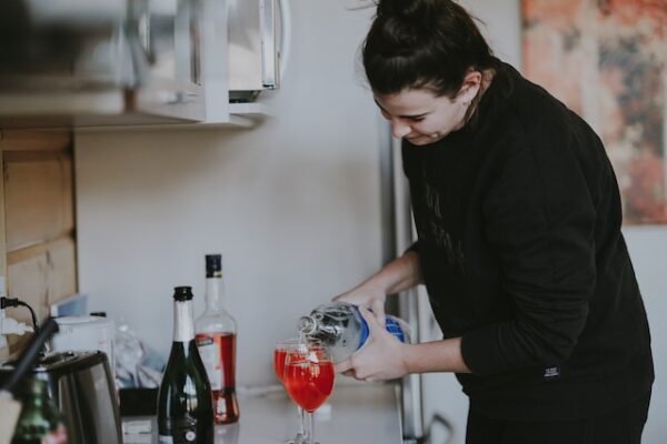Eine Frau befüllt Gläser in ihrer Küche mit Sekt und anderen getränken