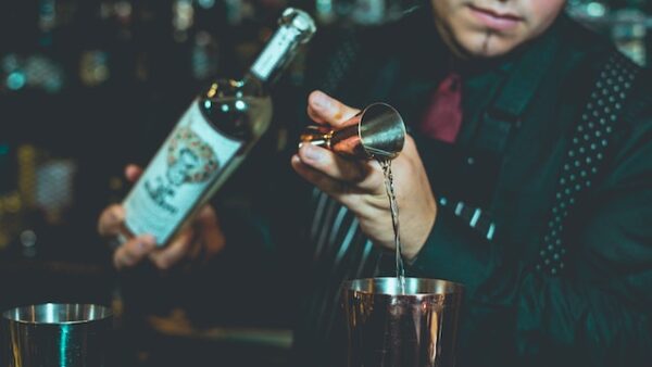 Ein Barkeeper füllt Alkohol mit einem Jigger in einen Shaker.