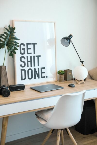 Ein ordentlicher Schreibtisch mit Zimmerpflanzen und einem motivierenden Bild, auf dem "GET SHIT DONE" steht. 