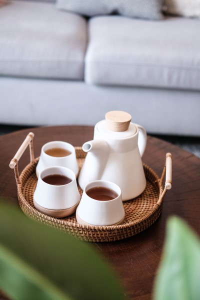 Auf einem Wohnzimmer tisch steht ein Tablett mit Teekanne und drei Teeschalen.