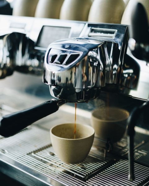 Eine Kaffemaschine brüht Espresso in eine Tasse. 