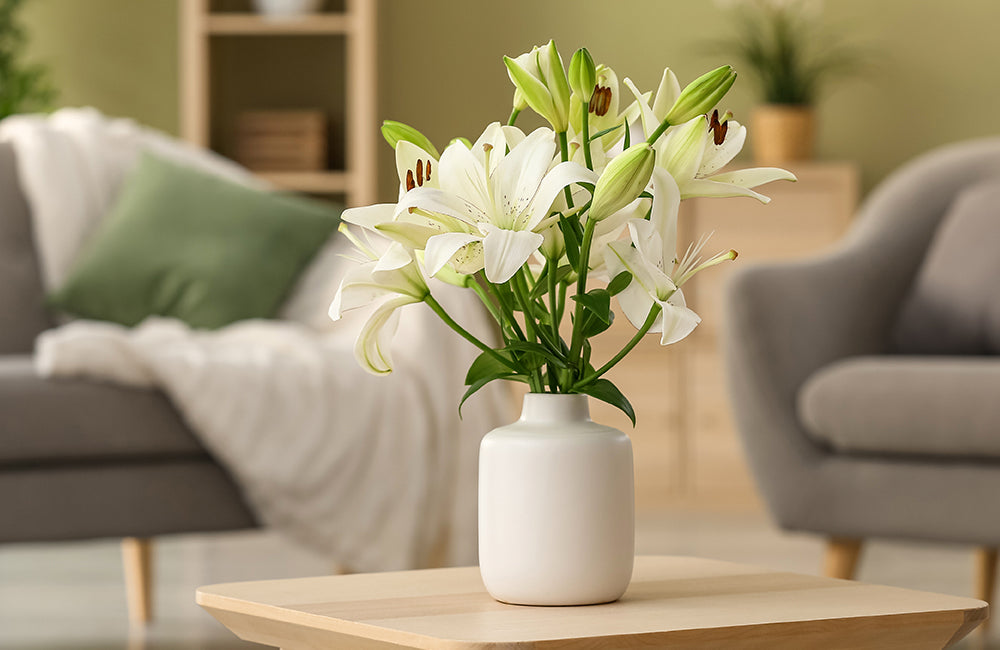 Schöne Lilienblumen in einer weißen Vase auf einem Tisch.