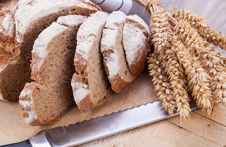 Aufgeschnittenes Brot mit einem Messer und Getreide.
